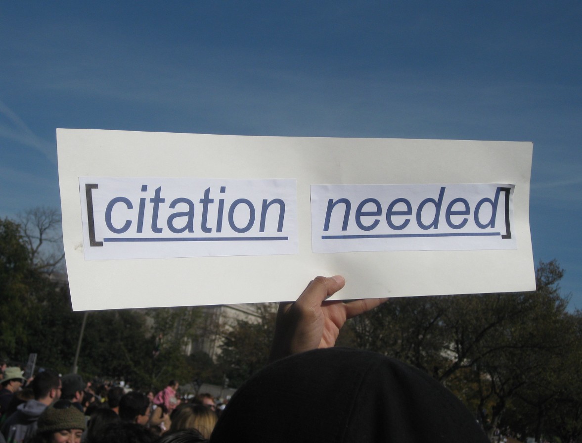 a protestor's sign reads "citation needed"