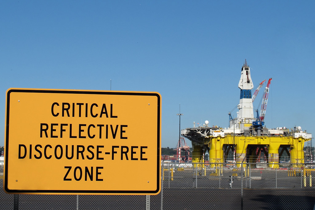 Protestors in Seattle erect the sign "Critical Reflective Discourse Free Zone" to challenge voters to consider the potential environmental impact of an oil spill from Shell Oil's drilling operations in Alaska’s Chukchi Sea.