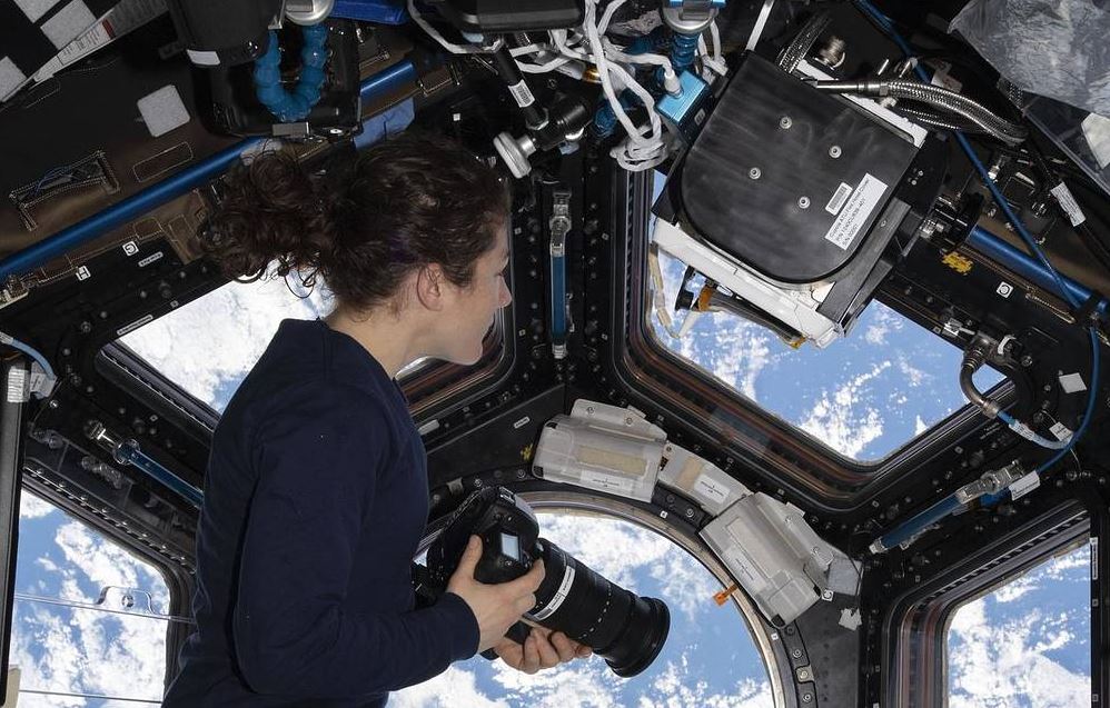 Collaboration tools - female astronaut looking out of the cupola on the international space station