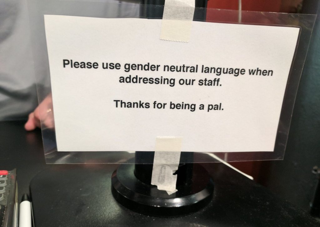 This sign reads "Please use gender-neutral language when addressing staff," which illustrates the importance of correct pronoun usage.